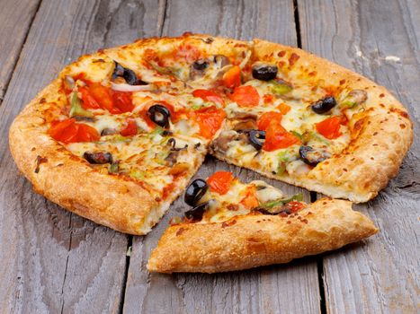 Full Body and Slice of Vegetarian Pizza with Tomatoes, Black Olives and Cheese on Rustic Wooden background