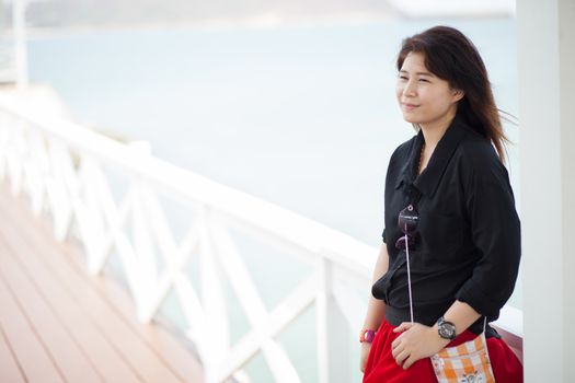 Asian women black jacket Smiling stood on a bridge made ������of wood.
