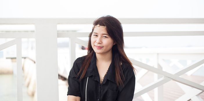 Asian woman smiling in black shirt and white wooden terrace.