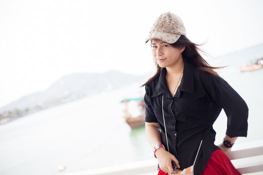 Asian women black shirt Standing near wooden terrace Behind the Sea