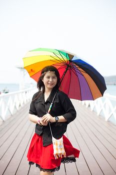 Asian women black shirt Standing holding an umbrella in the middle of the bridge Behind the sea and the sky during the day.