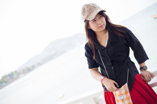 Asian women black shirt Standing near wooden terrace Behind the Sea