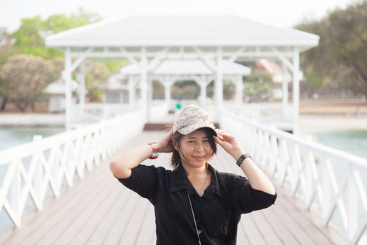 Asian women black shirt. She is wearing a hat Standing in the middle of the bridge