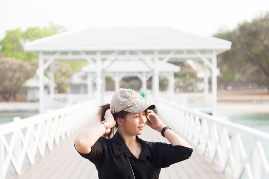 Asian women black shirt. She is wearing a hat Standing in the middle of the bridge