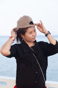 Asian women black shirt. She was wearing a hat In the background is the sea in the evenings.