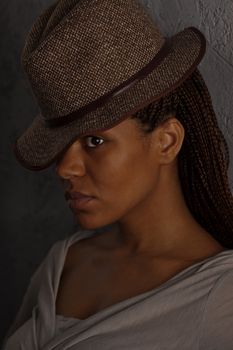 dark portrait of a black girl in gray hat