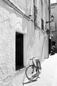 Spanish town street with a bicycle at a white wall, black and white photo