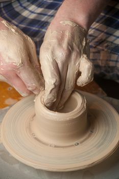 Hands of a potter, creating an earthen jar on the circle