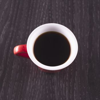 Red cup of coffee seen from above, wooden background