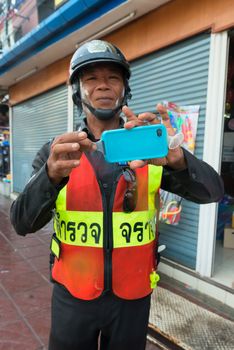 Phuket, Thailand - April 13, 2014: Police officer shows how to protect phone during celebration Songkran Festival, the Thai New Year from splashing water. 