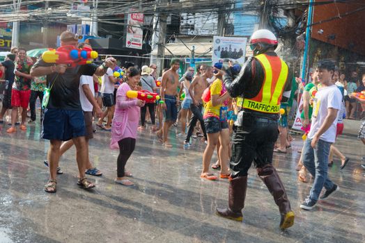 Phuket, Thailand - April 13, 2014: Tourist and police officer celebrate Songkran Festival, the Thai New Year by splashing water to each others on Patong streets. 