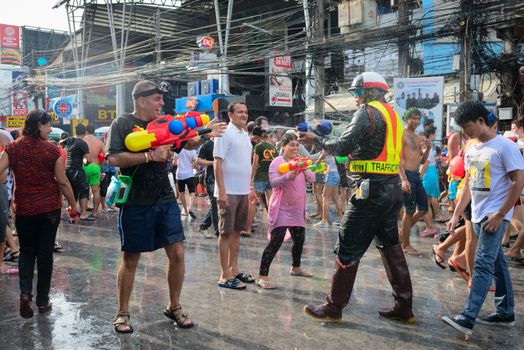 Phuket, Thailand - April 13, 2014: Tourist and police officer celebrate Songkran Festival, the Thai New Year by splashing water to each others on Patong streets. 