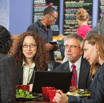 Group of executives meeting over lunch with laptop