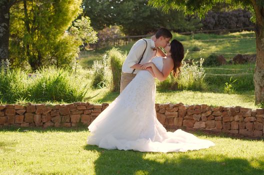 Bride and groom kissing in outside garden wedding ceremony