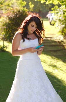 Bride texting on phone outside church on way to wedding