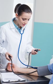 Female doctor or nurse with patient measuring blood pressure 