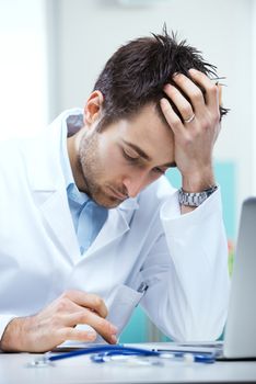 Yound handsome doctor working with a tablet at his desk.