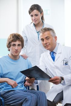 Doctor and assistant examining an x-ray image with a patient in wheelchair.