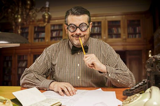 Pensive office employee with a pencil in his mouth looking up in the 1960s