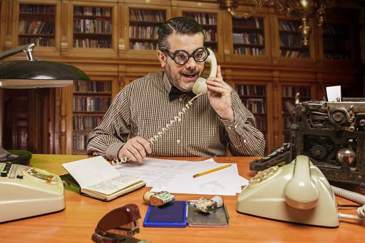 Employee with glasses talking on the phone in the office in the 1960s