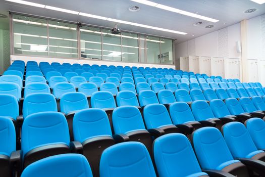 Interior of empty conference hall with blue velvet chairs.