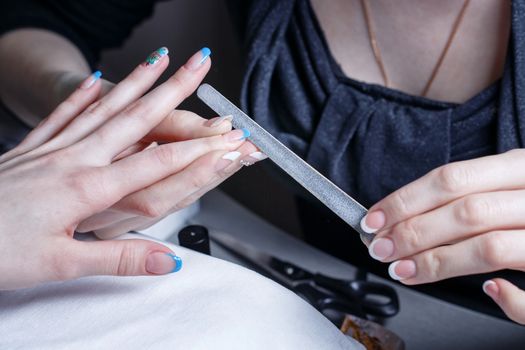 Manicurist nails handles client nail file shot closeup