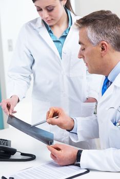 Medical team examining an x-ray image and pointing with a pen.