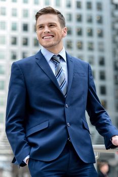 Young businessman standing with hands in pockets
