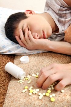 Teenager sleeps near the Pills on the Bed at the Home