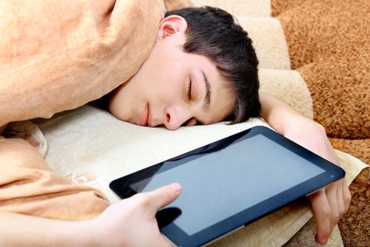 Tired Teenager sleeping on the Bed with Tablet Computer