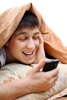 Cheerful Teenager with Cellphone under Blanket at the Home