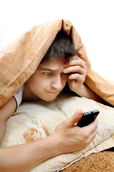 Stressed Teenager with Cellphone under Blanket at the Home