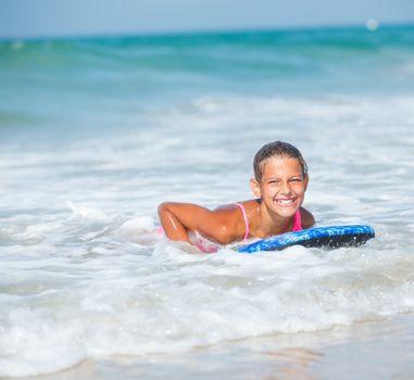 Summer vacation - Happy cute girl having fun with surfboard in the ocean