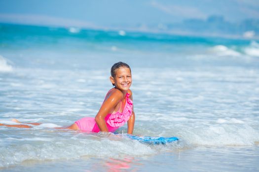 Summer vacation - Happy cute girl having fun with surfboard in the ocean