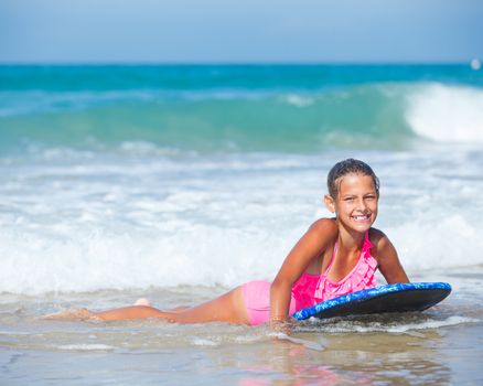 Summer vacation - Happy cute girl having fun with surfboard in the ocean