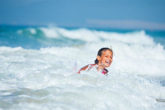 Summer vacation - Happy cute girl having fun with surfboard in the ocean