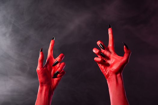 Creepy red devil hands with black sharp nails, Halloween theme  