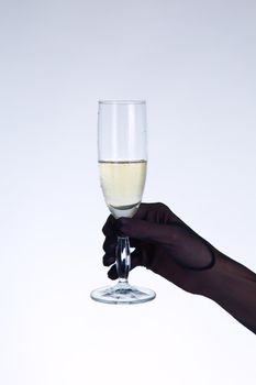 Female hand in black opera glove holding champagne glass, studio shot on gray background  