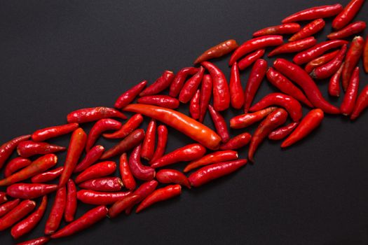 Row of non-stem red bird eye chili peppers on grey background 