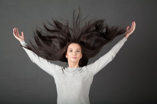 Woman on a gray background hair throws up.