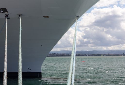 Bow of a cruise ship docked in the harbor with the focus on the bollards and ropes mooring the boat to the harbour wall