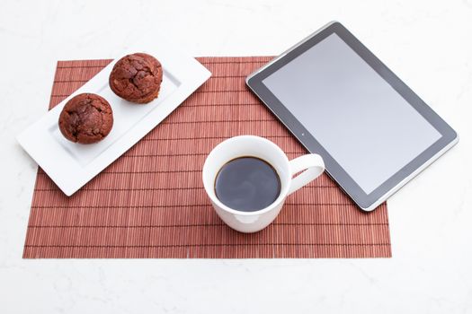 Chocolate chips Muffins with  a cup of coffee meanwhile using the tablet PC.