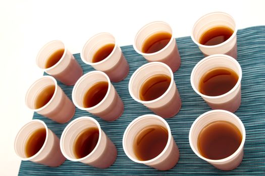 Lots of disposable cups with tea on a colorful background
