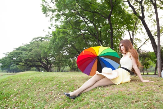 Woman sitting on the grass in the park. Posture relaxed and happy.