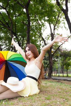 Woman sitting on the grass in the park. Posture relaxed and happy.