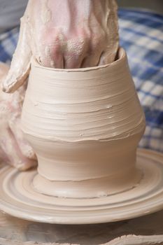 Hands of a potter, creating an earthen jar on the circle