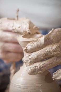 Hands of a potter, creating an earthen jar on the circle