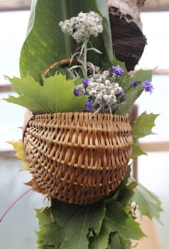 Autumn arrangement flowers and leaves in wicker basket