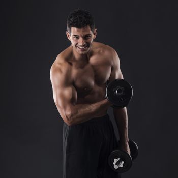 Portrait of a muscular man lifting weights against a dark background