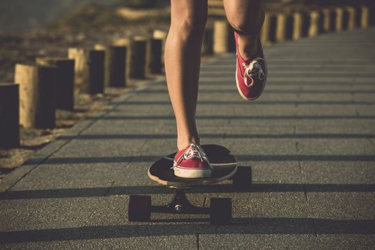 Young woman down the street with a skateboard